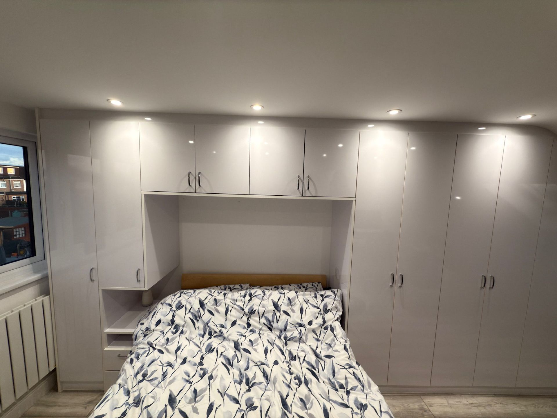 High-gloss white overbed fitted furniture with downlighting