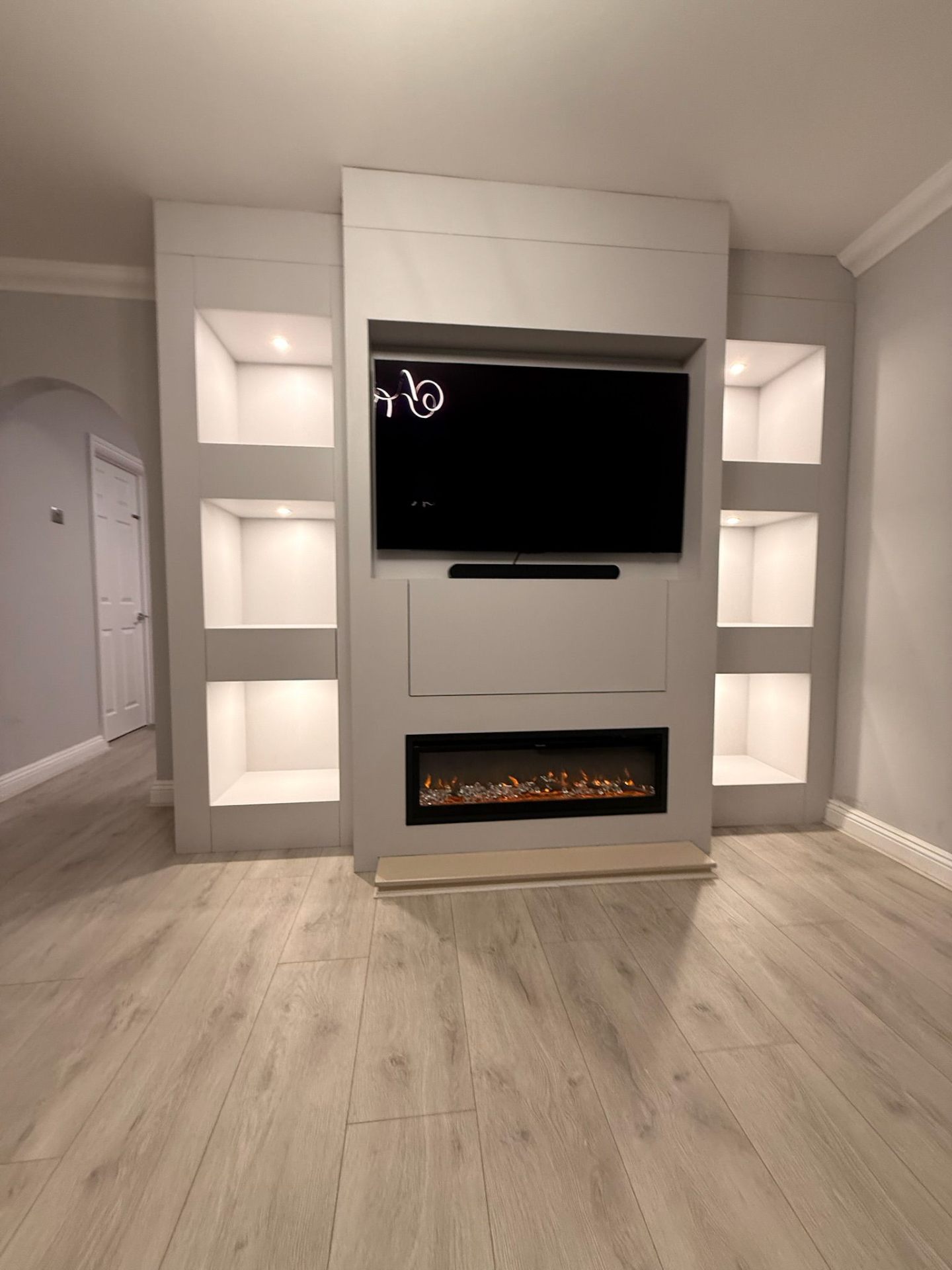 Bespoke media wall with recessed TV, electric fireplace and illuminated display niches