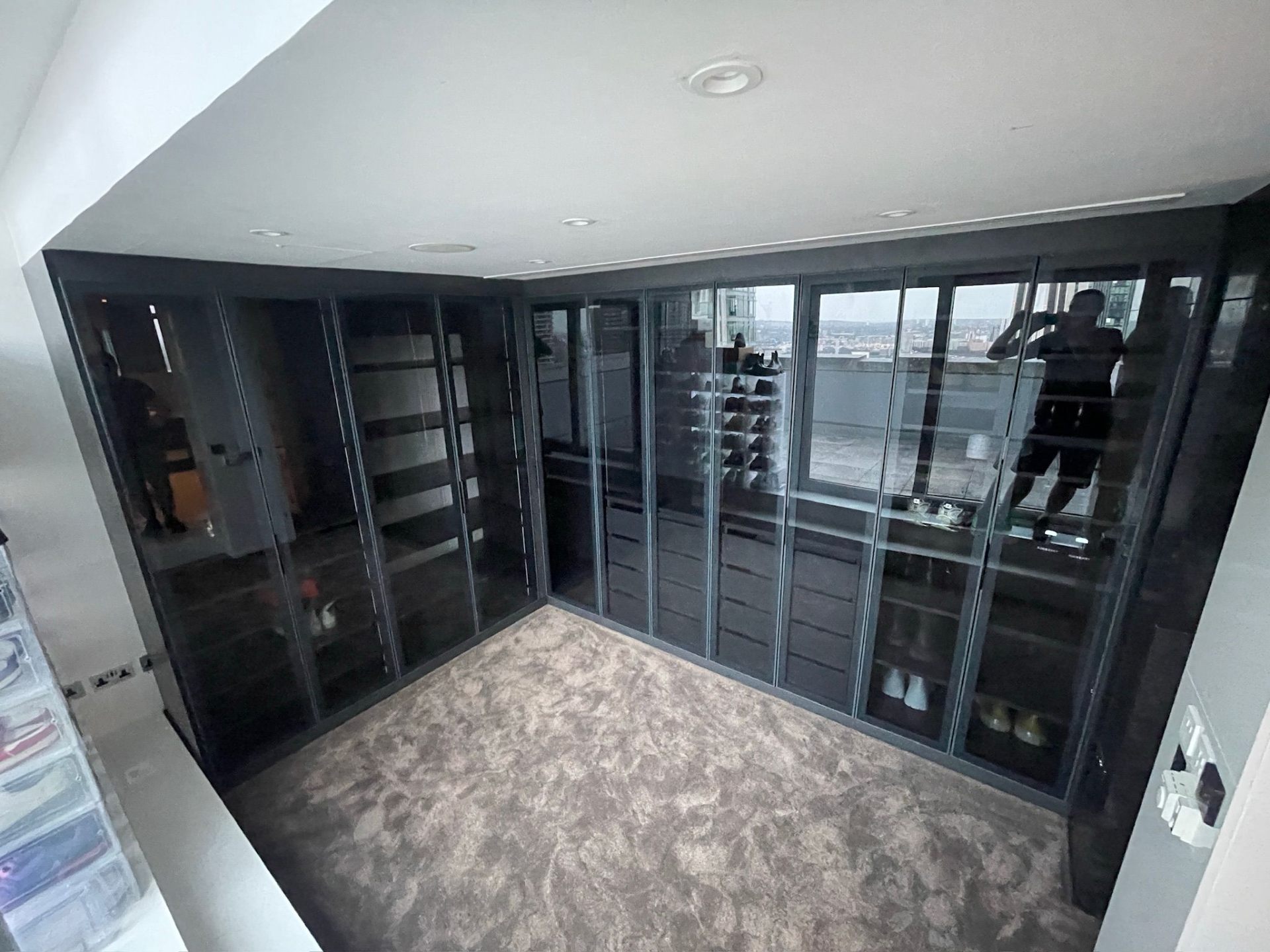 Walk-in wardrobe with black-framed glass doors and oak interior