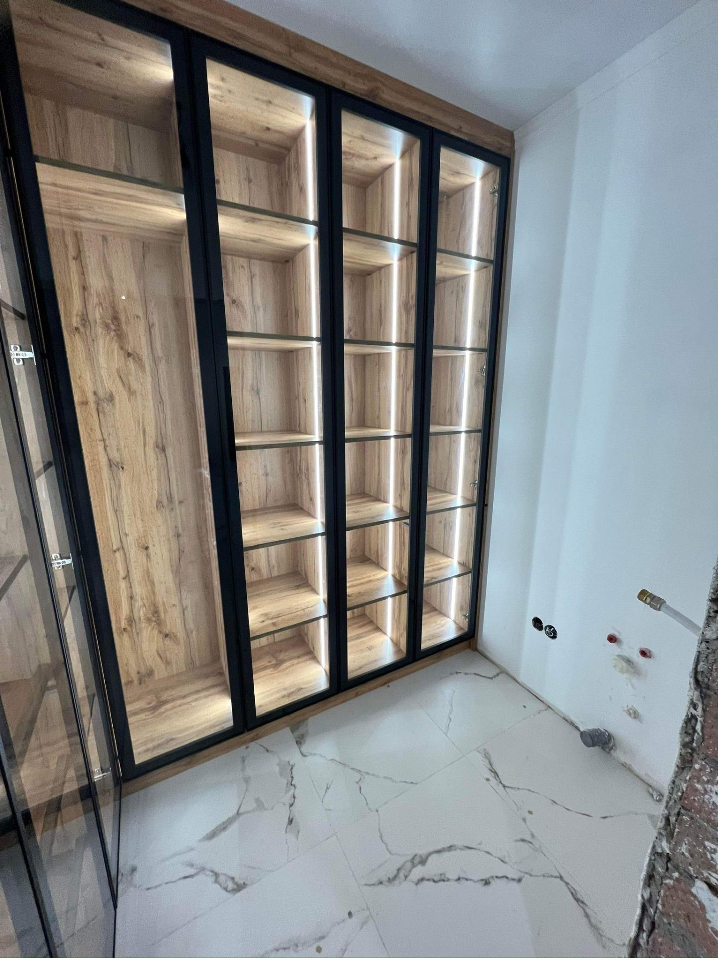 Front view of a walk-in wardrobe with black-framed glass and oak veneer