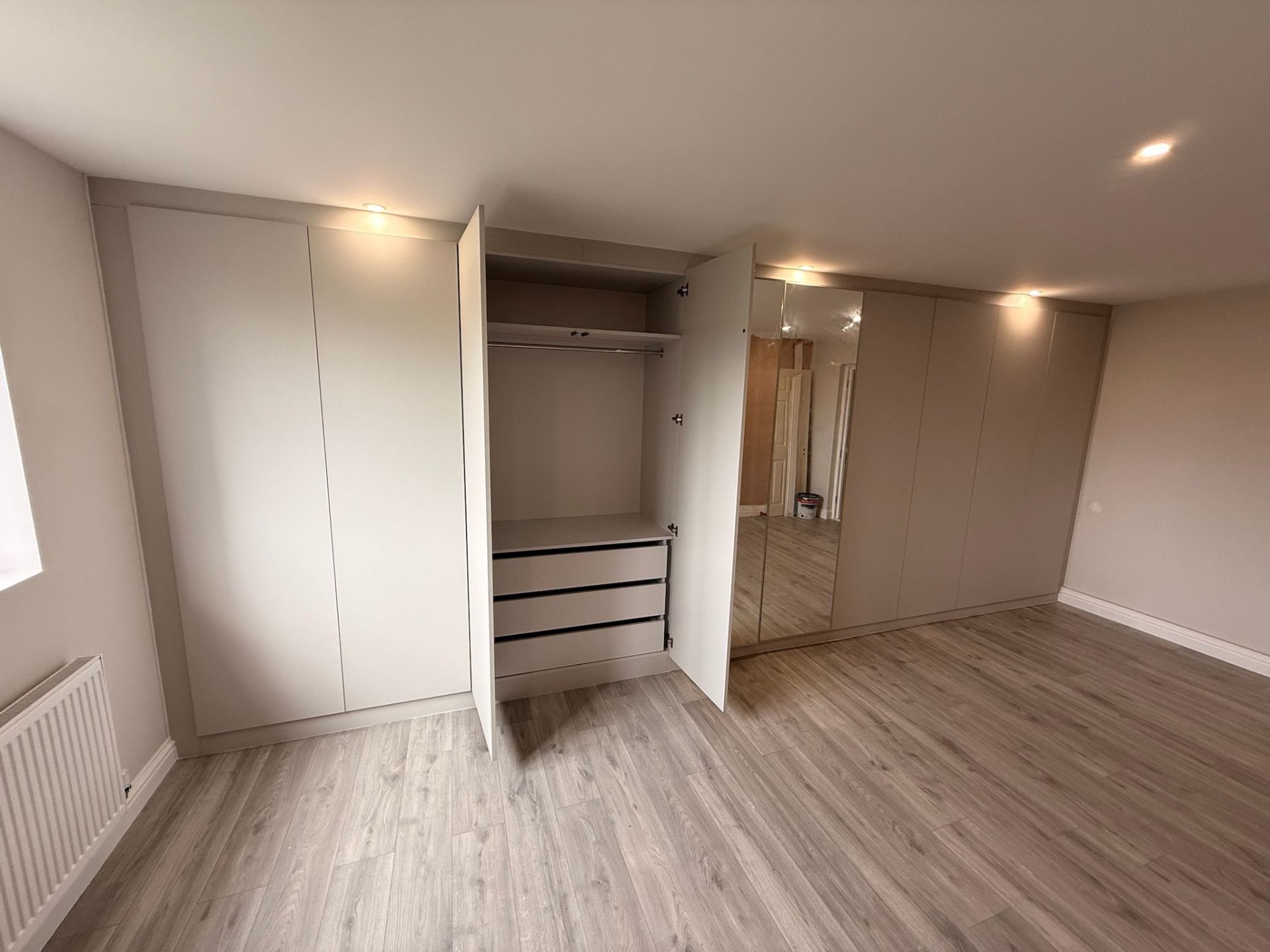 Full wall fitted wardrobe open showing complete interior layout with drawers and rails