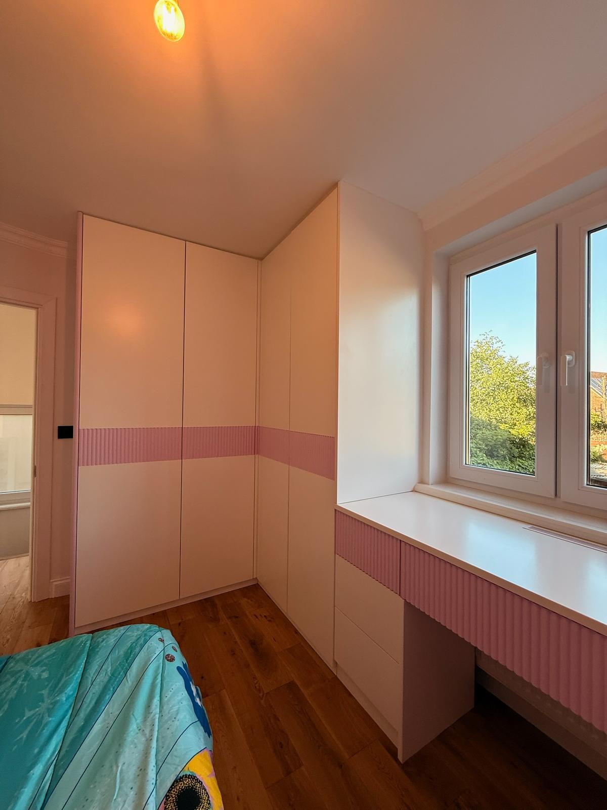 Children's fitted wardrobe in pink and white with integrated desk