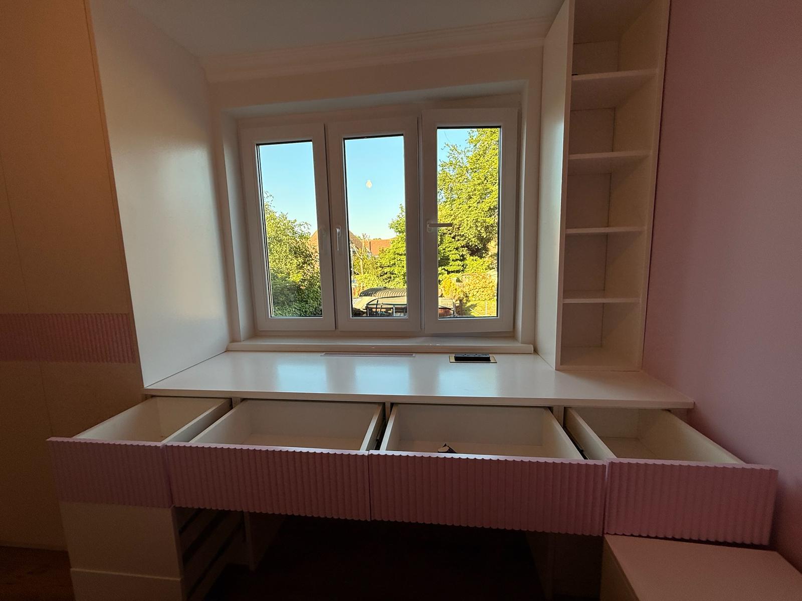 Pink fluted drawer unit under window with open shelving