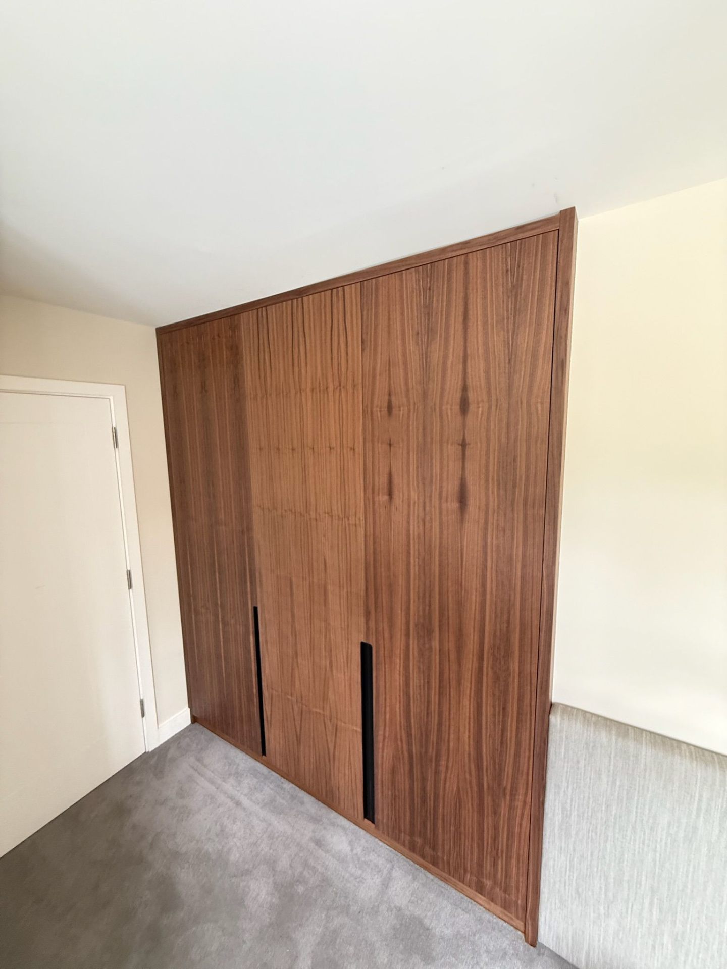 Walnut veneer fitted wardrobe with warm LED lighting