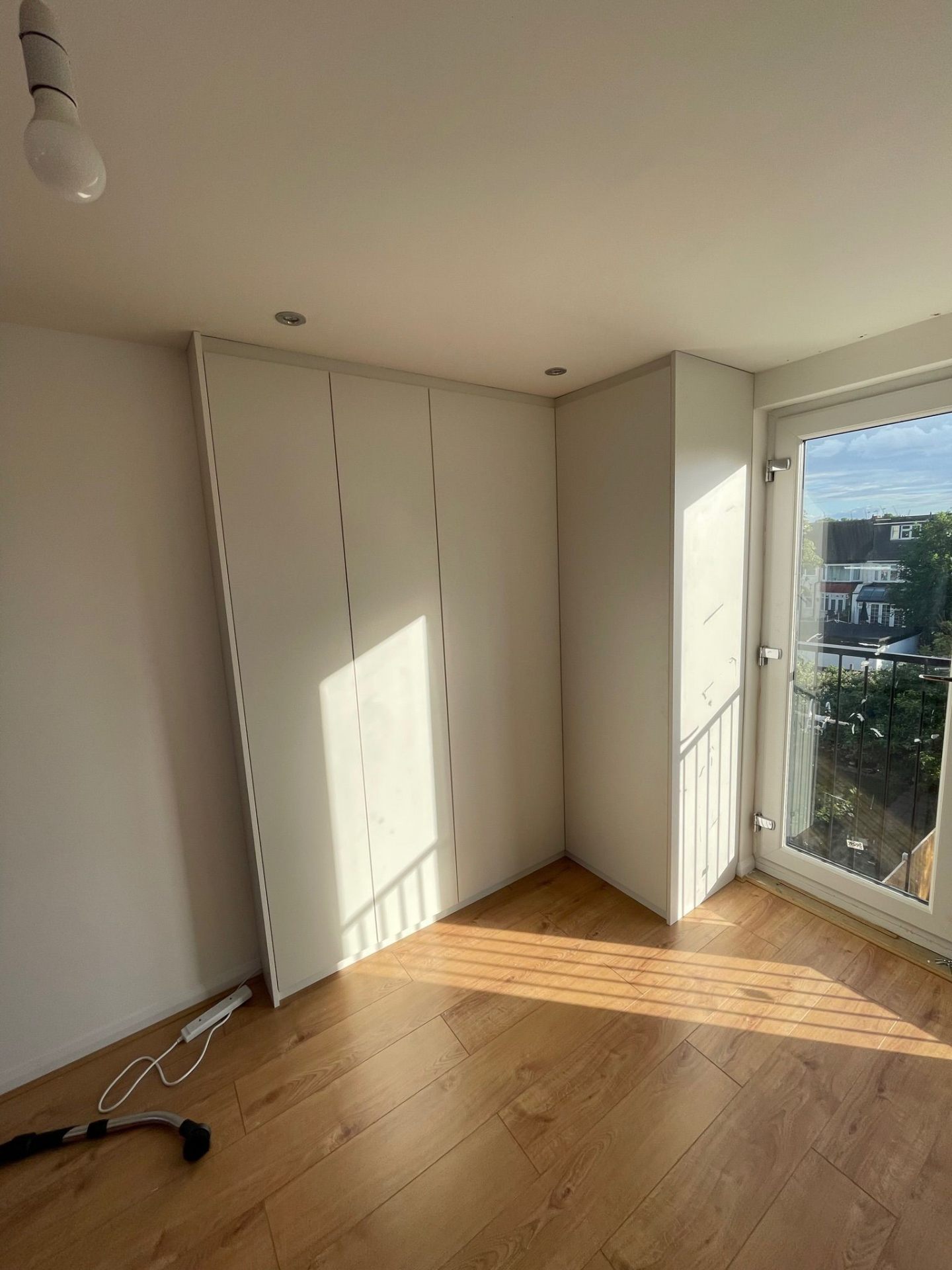 White handleless fitted wardrobe beside balcony door in a modern flat
