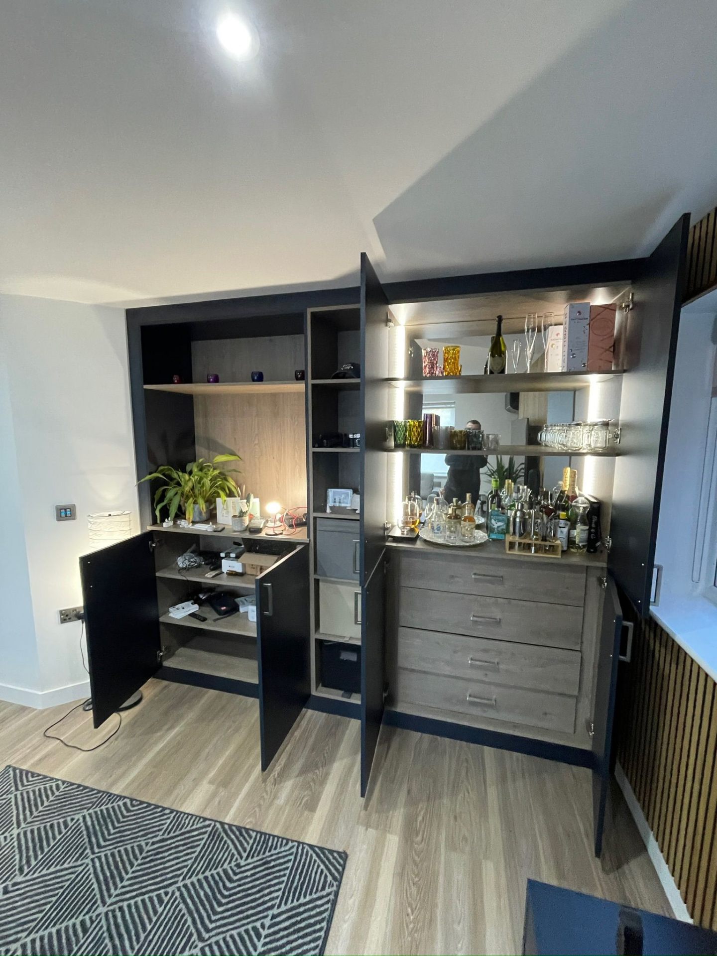 Wine bar cabinet open showing LED-lit display shelves and mirrored back